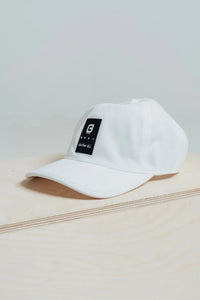 Blizzard White mesh golf hat with a black Give Your All patch on a wooden box
