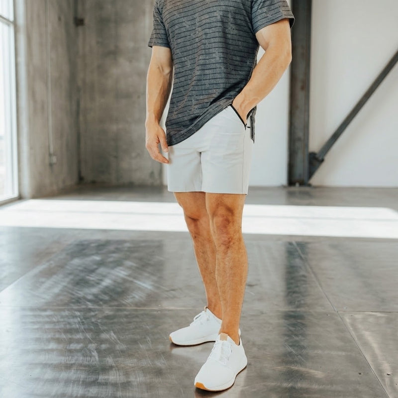 Pebble Grey 6 inch inseam golf shorts worn with a heathered grey tee and white sneakers