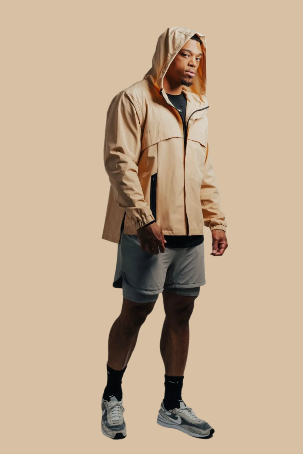 Man in a sand-colored King's Gold Stealth jacket with hood up