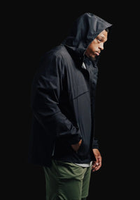 Black Stealth full-zip rain jacket worn with the hood up, side view