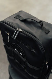 Soft-focus detail of the black Ai1 backpack's matte shell and branded zipper pulls