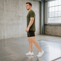 Side view of a man walking in black 6 inch golf shorts and white sneakers, showing the above-knee length