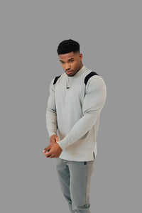 Ghost Grey/Black men's long sleeve golf shirt, hands clasped, grey studio backdrop