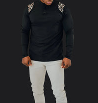 Black long sleeve golf shirt with camo shoulder panels, worn with light grey pants