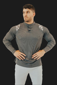 Man with hands on hips in the Storm Grey/Camo long sleeve golf shirt, dark backdrop