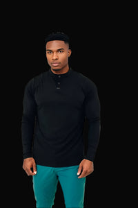 Man in the All Black long sleeve golf shirt with a button placket, worn with teal pants