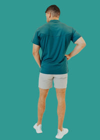 Back view of the Pine Green short sleeve golf shirt, hand on hip