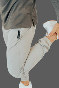 Close-up of the woven tab and cuff on Ghost Grey golf joggers, knee raised