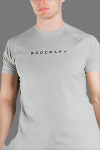 Close-up of the BODCRAFT chest logo on a Sandstone Grey short sleeve workout shirt
