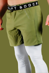 Front view of Army Green training shorts worn over white base-layer leggings, BodCraft waistband