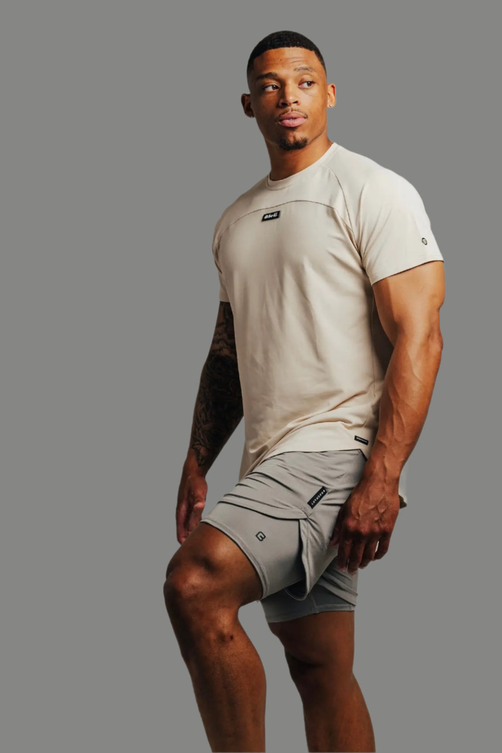 Ghost Grey Ai1 lined training shorts with a sand-colored tee, grey backdrop