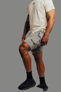 Ghost Grey lined training shorts mid-step with a phone in the liner pocket, sand tee