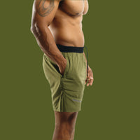 Dark Olive men's training shorts from the side, hand in pocket