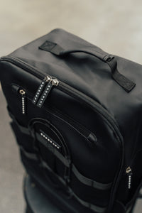 Midnight Black Ai1 backpack detail: grab handle, zip pulls and bungee cord on the front panel