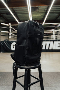 Black Ai1 gym backpack standing on a stool in front of a boxing ring